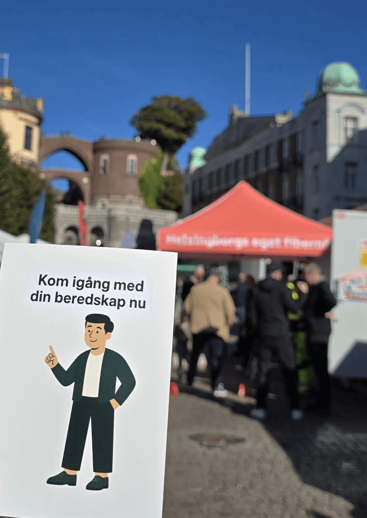 A Bereddo flyer reading 'Kom igång med din beredskap nu' held up at the company's stand at an outdoor preparedness event in Helsingborg.